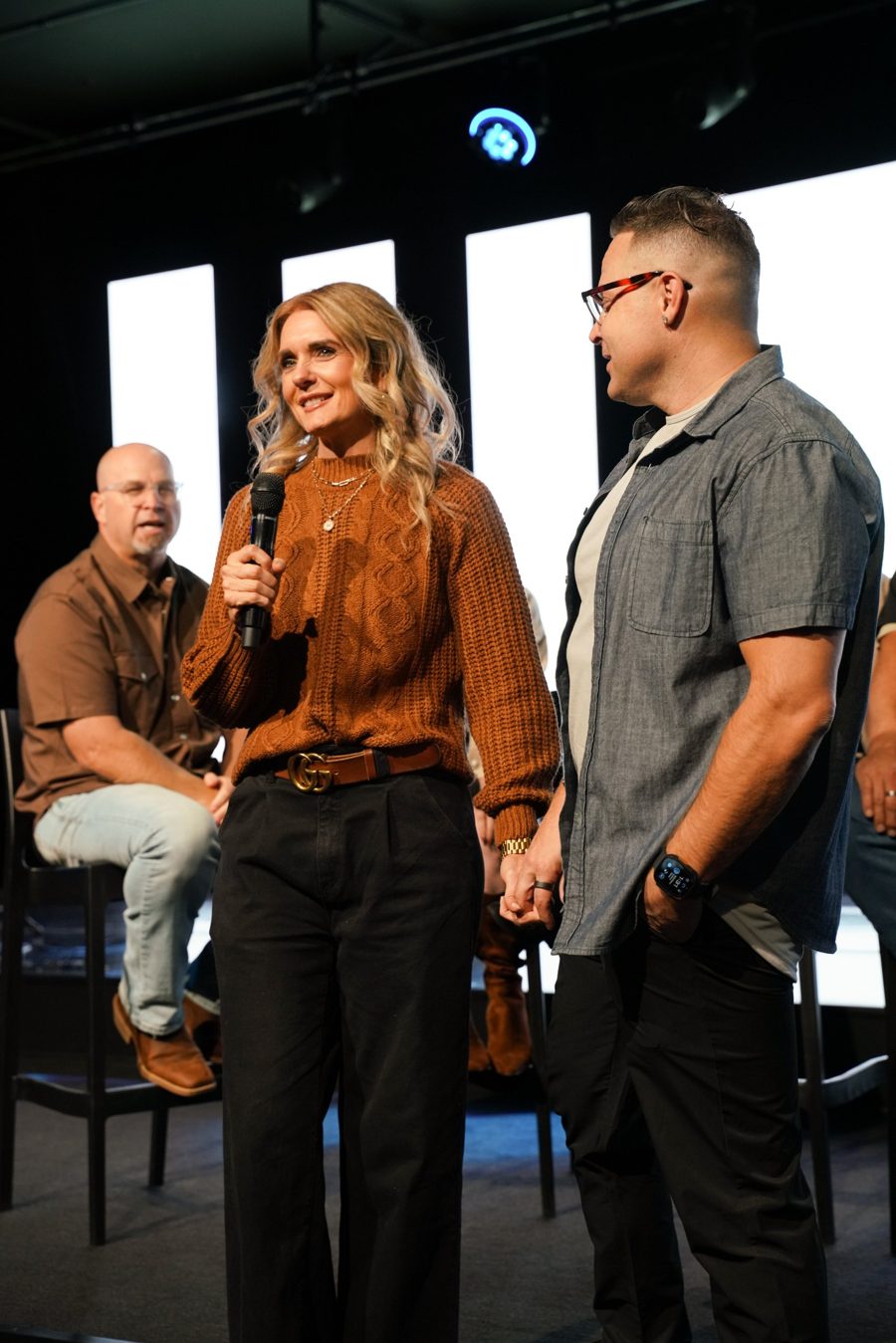 Jami sharing on stage with Tom beside her